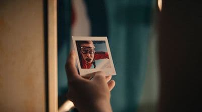 a person holding a polaroid with a picture of a man