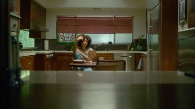 a woman standing in a kitchen next to a table