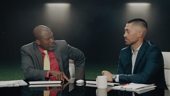 two men sitting at a table talking to each other