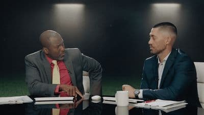 two men sitting at a table talking to each other