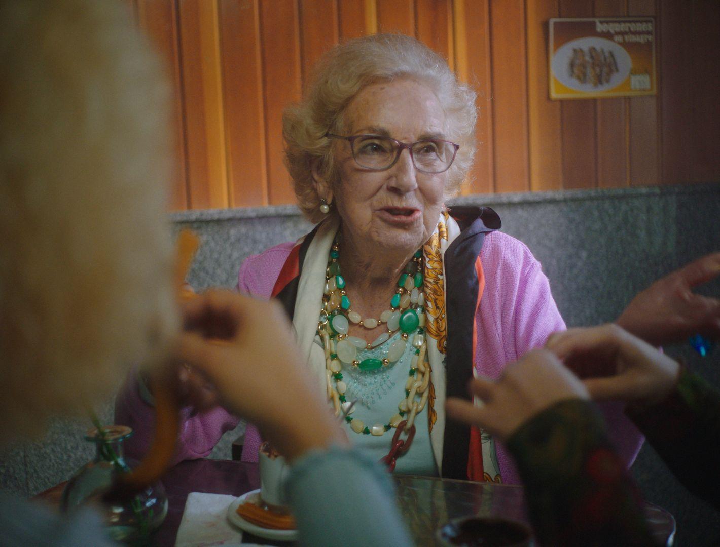 a woman in a pink shirt is talking to a group of people