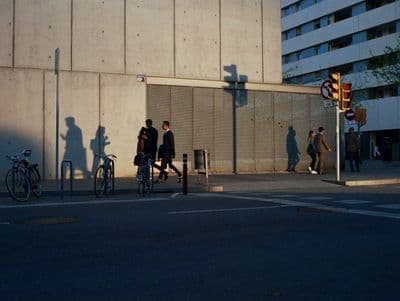 a group of people walking down a street next to a tall building