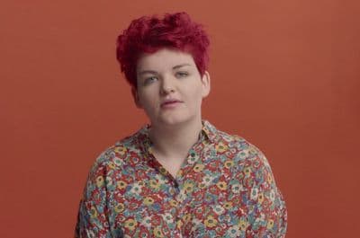 a woman with red hair wearing a floral shirt