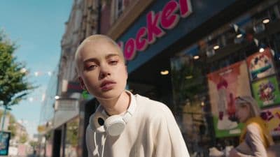 a woman with white hair and headphones standing in front of a store