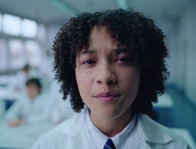 a young man with curly hair wearing a white shirt and blue tie