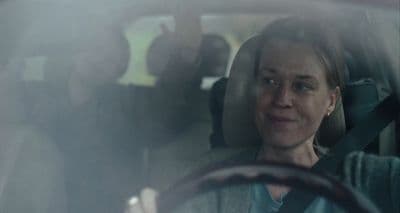 a woman sitting in a car with a steering wheel