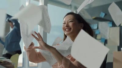 a woman in a pink dress is throwing papers in the air
