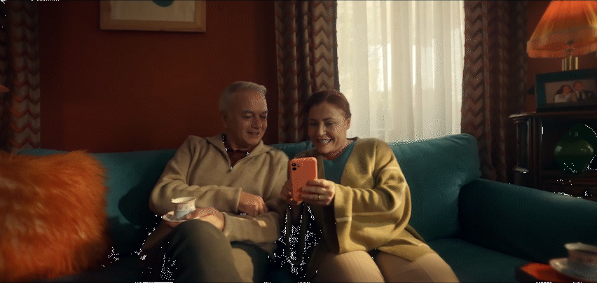a man and woman sitting on a couch looking at a cell phone