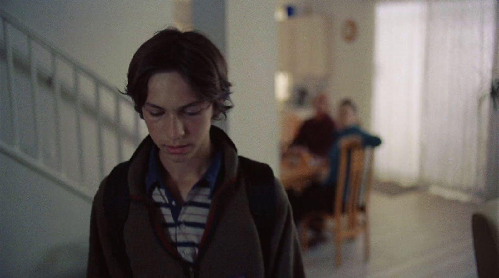 a young man standing in a hallway looking at his cell phone
