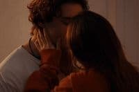 a man and a woman kissing in front of a mirror