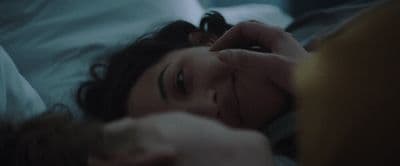 a woman laying in bed with her hand on her head