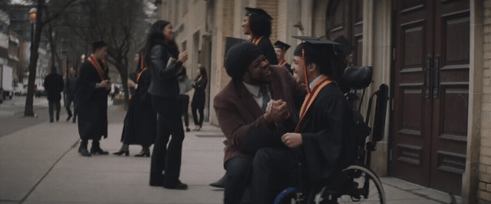 a man in a wheelchair talking to a woman in a graduation gown