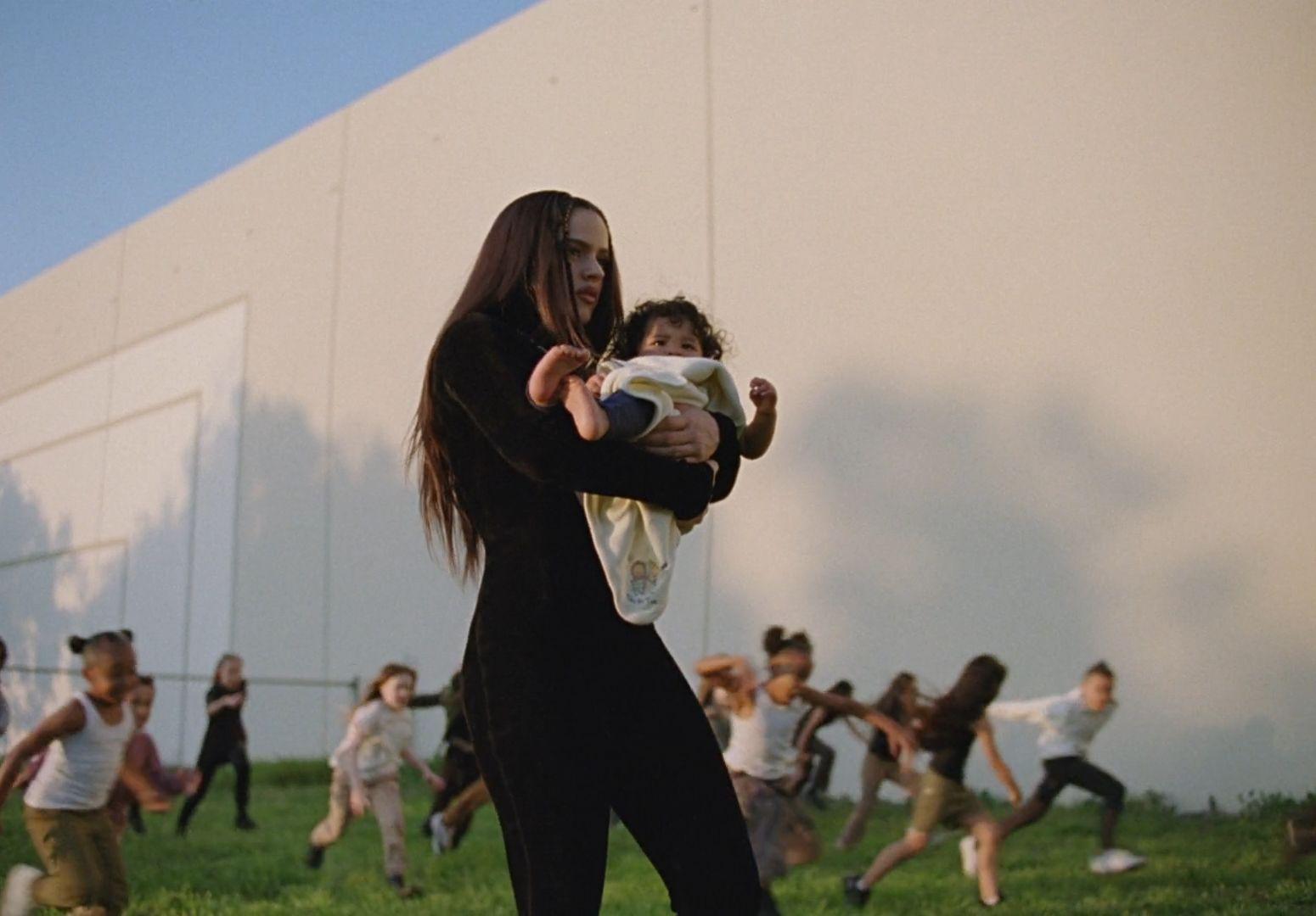 a woman holding a baby in her arms in front of a group of people