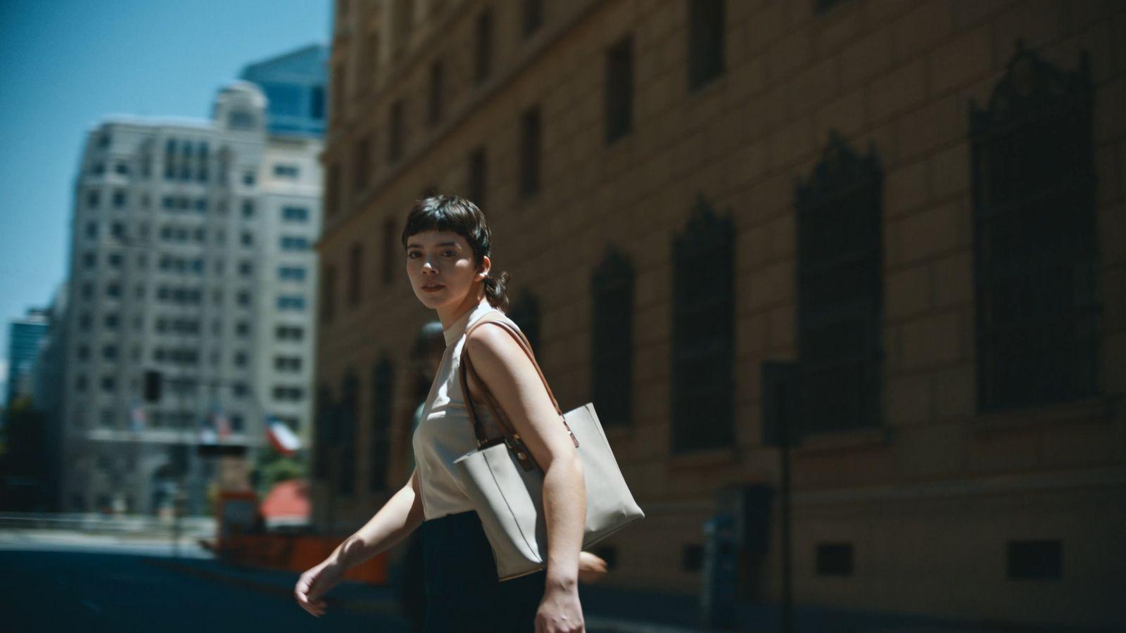 a woman walking down a street holding a bag