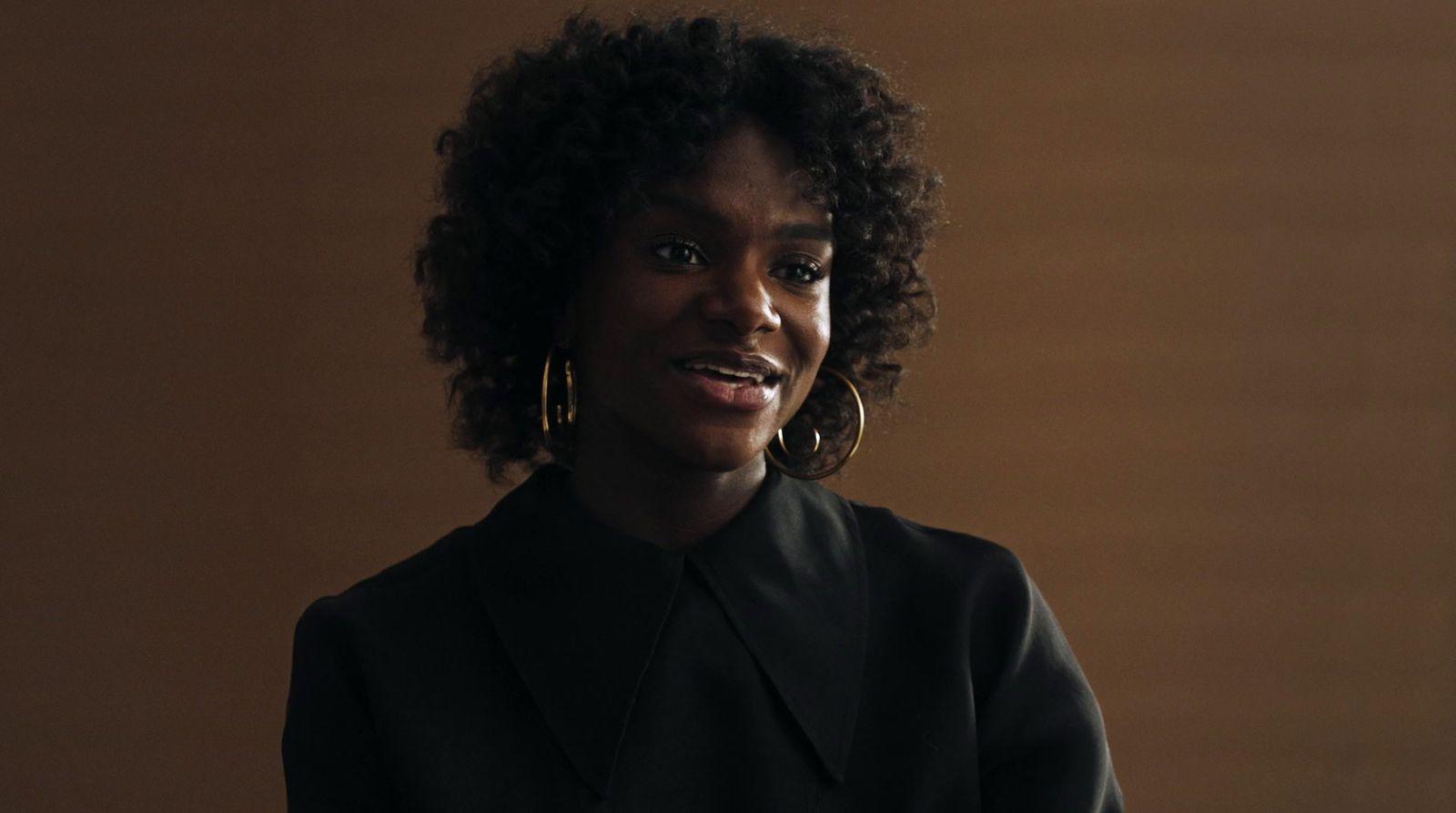 a woman wearing a black jacket and earrings