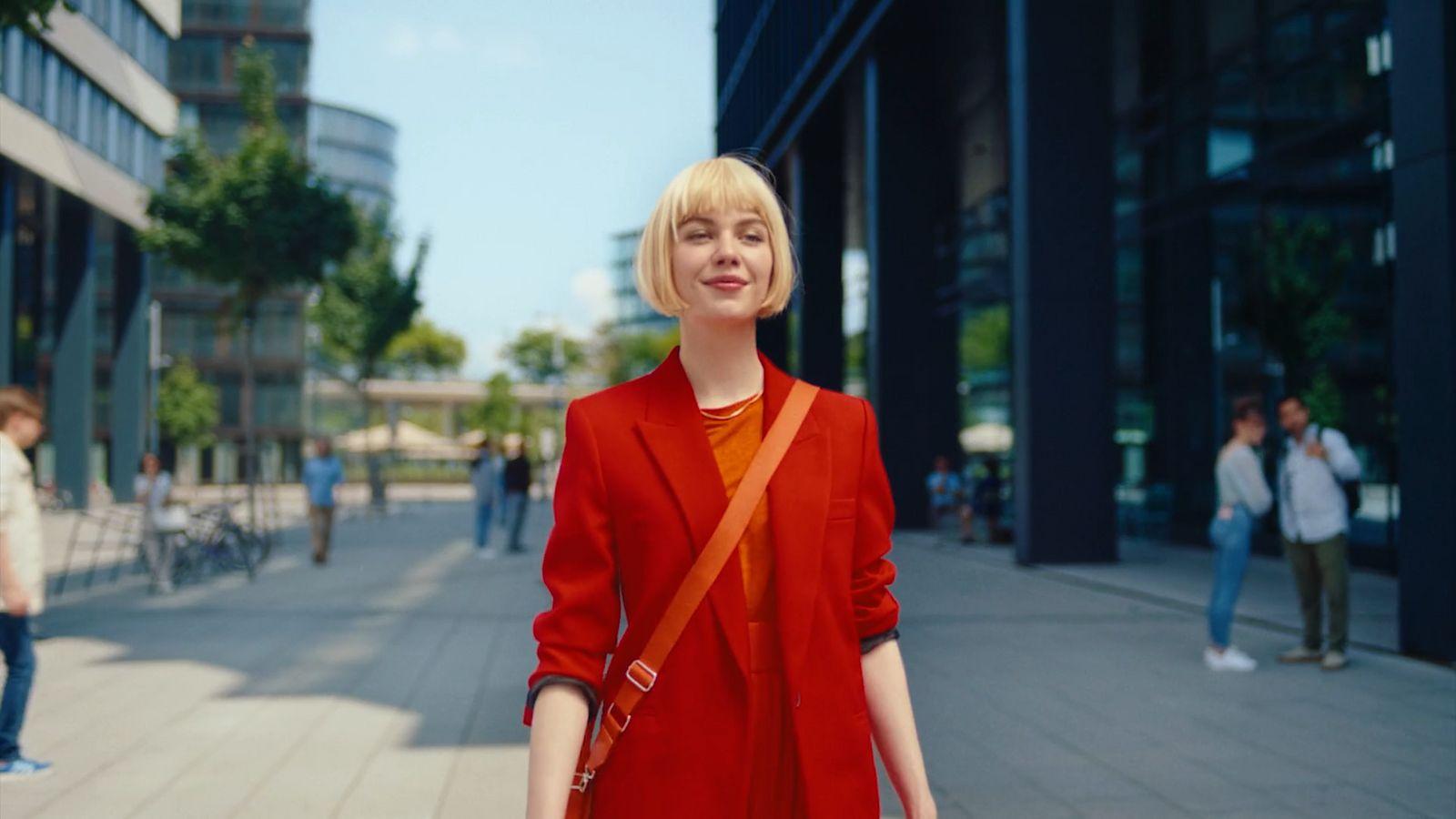 a woman in a red coat is walking down the street