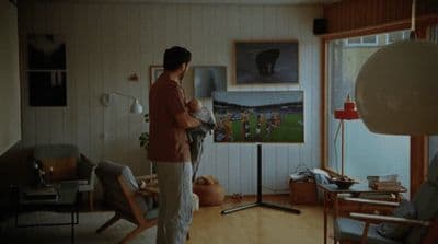 a man standing in a living room next to a window