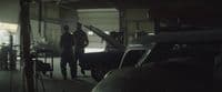 a couple of men standing next to a car in a garage
