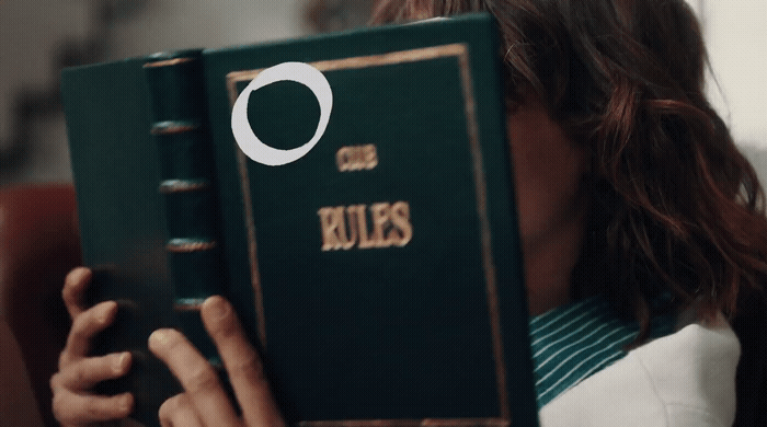 a woman holding a green book with the word rules on it