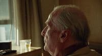a man sitting in a chair looking out a window