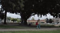 a woman walking down a street with a red bag