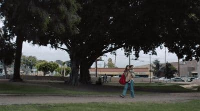 a woman walking down a street with a red bag