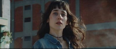 a woman in a denim jacket standing in front of a building