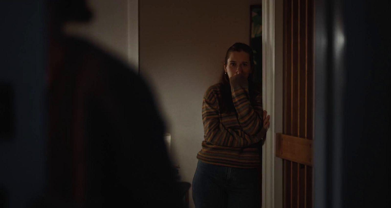 a woman standing in a doorway with her hand on her face