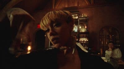 a woman standing in a room with a glass of wine