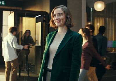 a woman in a green coat standing in front of a building