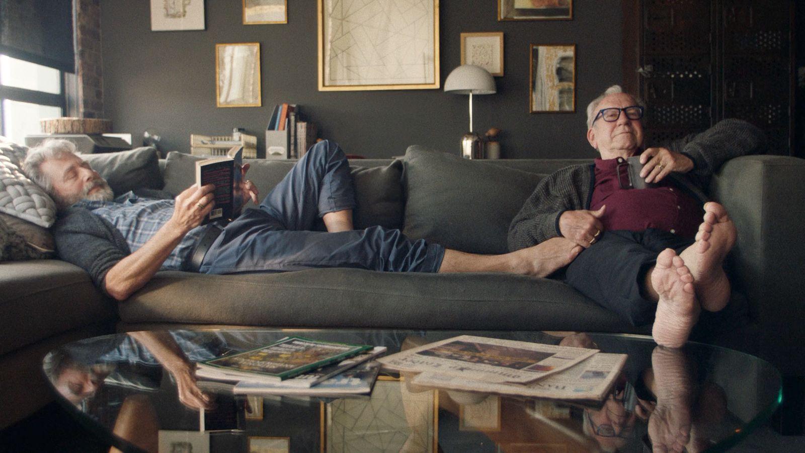 a man laying on a couch next to another man
