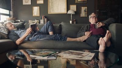 a man laying on a couch next to another man