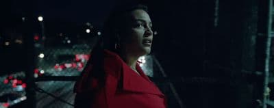 a woman in a red coat standing in the dark
