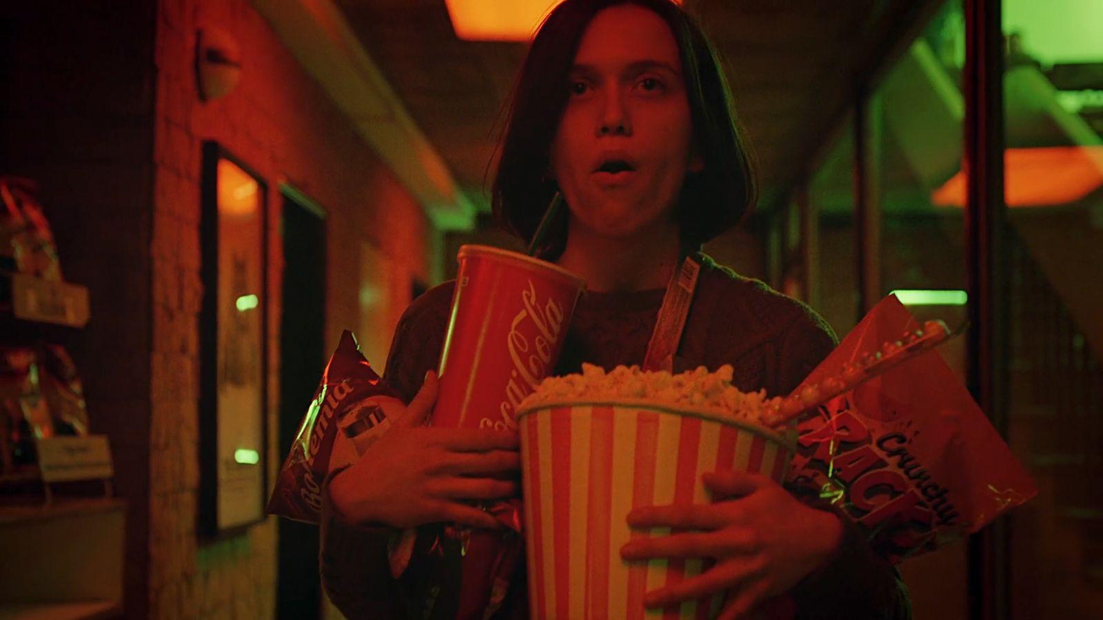 a woman holding two buckets of popcorn in her hands