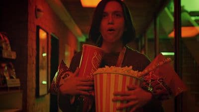 a woman holding two buckets of popcorn in her hands