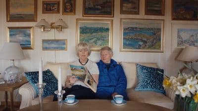a man and woman sitting on a couch reading a magazine