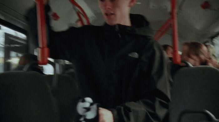 a young man sitting on a bus with his arms in the air