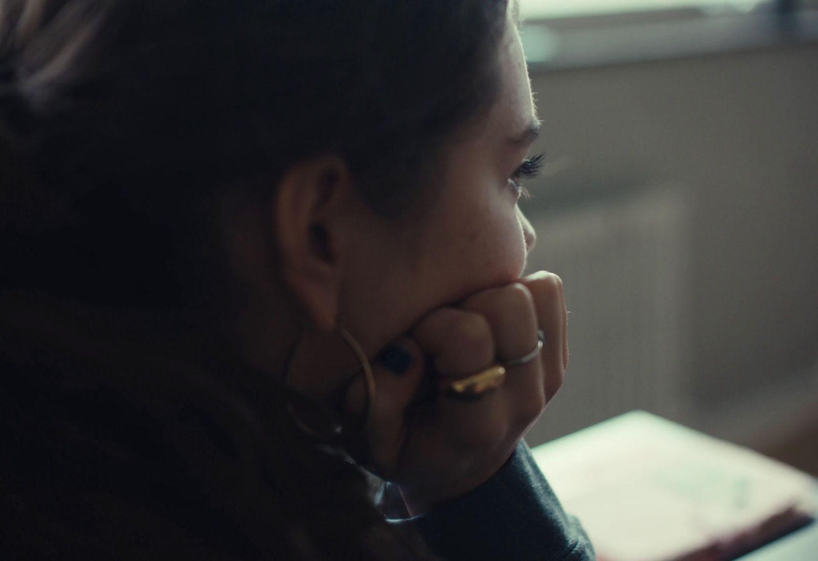 a woman sitting at a table with her hand on her face