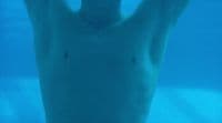 a man is swimming in the water with his hands up