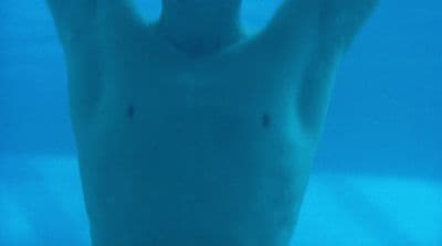 a man is swimming in the water with his hands up