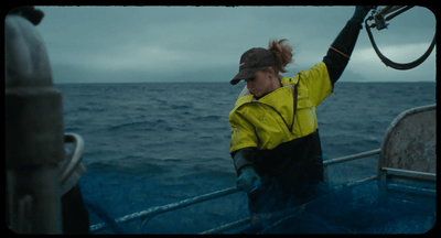 a woman in a yellow jacket on a boat in the ocean