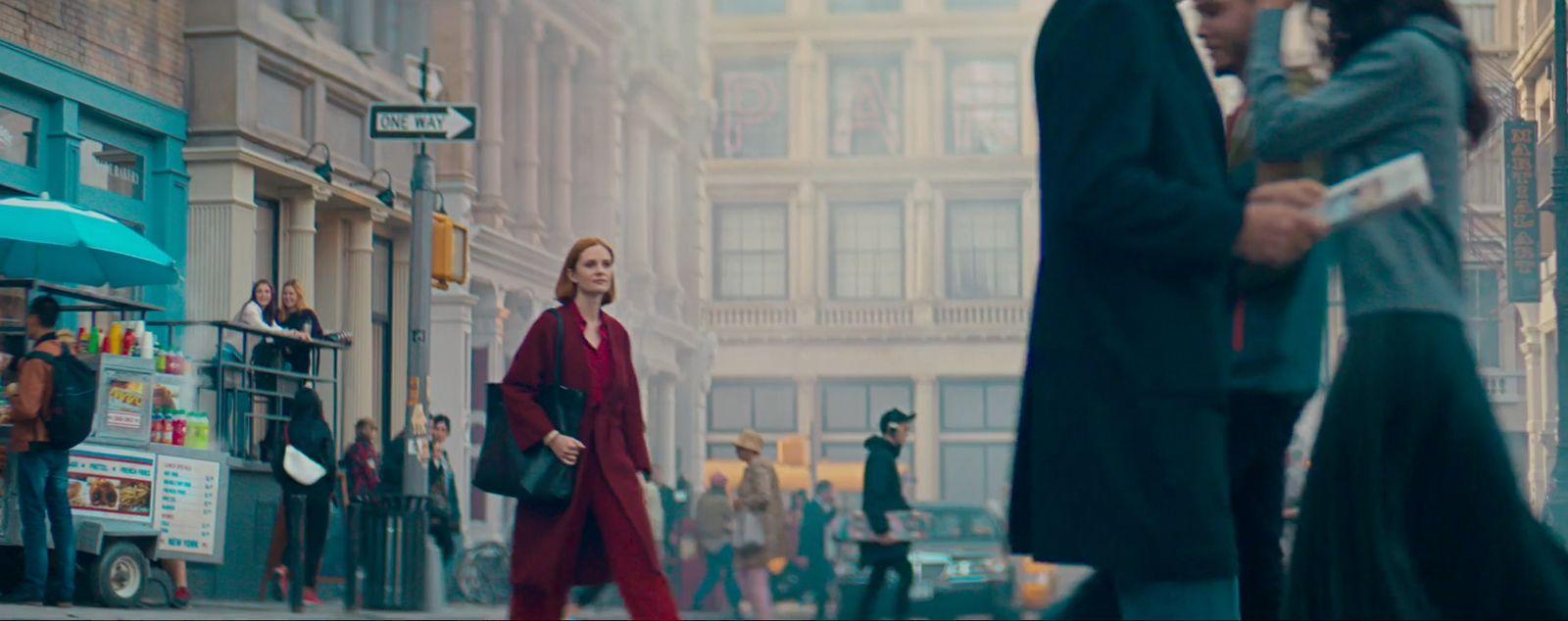 a group of people walking down a street next to tall buildings