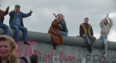 a group of people sitting on top of a cement wall