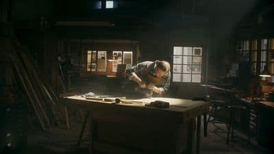 a man working on a piece of wood in a dark room