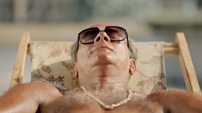 a man wearing sunglasses laying in a chair