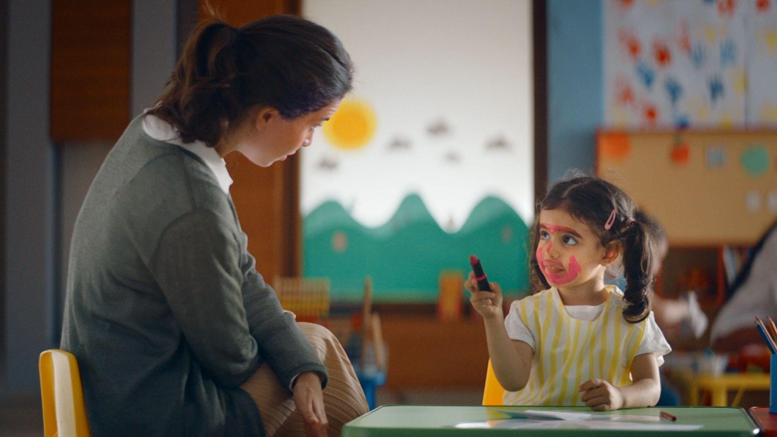 a little girl sitting at a table with a teacher