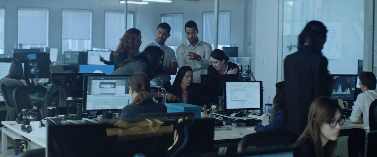 a group of people standing around a desk in an office