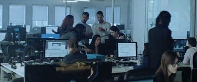 a group of people standing around a desk in an office