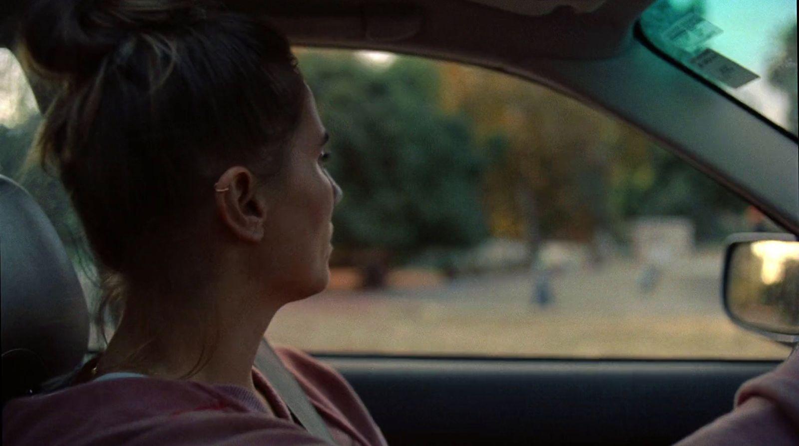 a woman driving a car in a parking lot