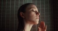 a woman with her eyes closed standing in front of a shower